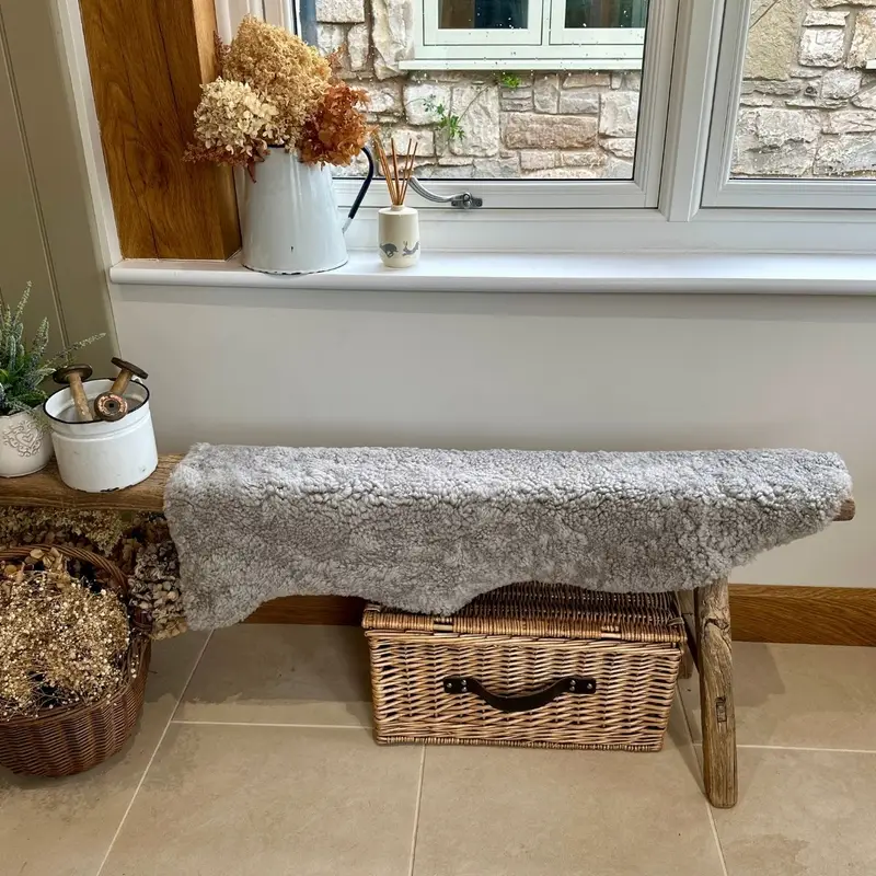 Short curly cloudy boucle sheepskin draped over a wooden horse in a bright hallway.
