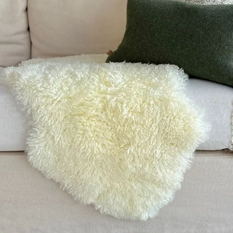 An off white curly sheepskin on a cream sofa.
