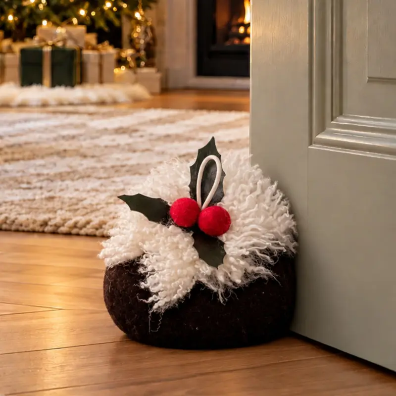 Handmade sheepskin Christmas pudding doorstop holding open a door to a beautifully decorated Christmas living room.