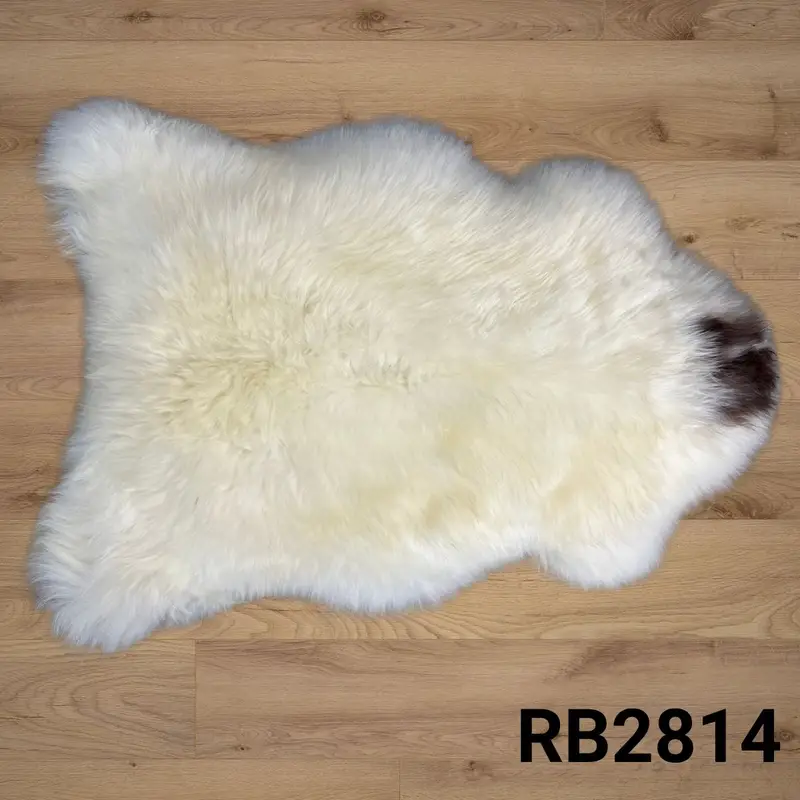 Natural rare breed sheepskin rug styled on warm wooden floorboards.
