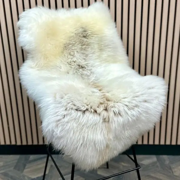Natural ivory Himalayan sheepskin rug styled on a metal bar stool, with flowing fleece softening the industrial frame.