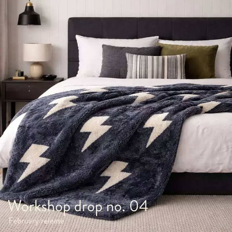 Lightning bolt sheepskin throw styled as a bedspread on a modern bed, featuring gunmetal grey sheepskin and oatmeal bouclé detailing.