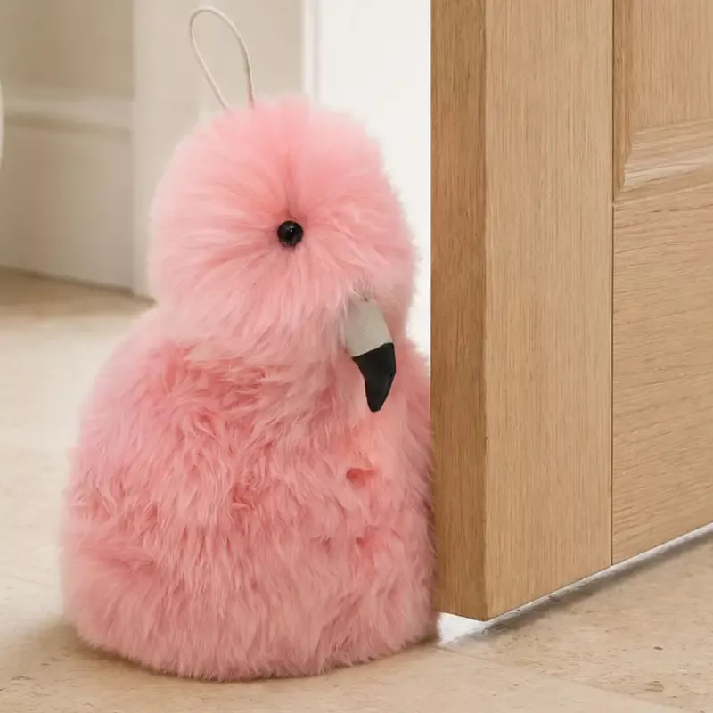 Close-up of a handmade flamingo sheepskin doorstop showing pink wool texture and playful bird details