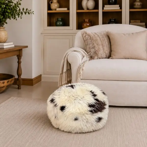 Round handmade rare breed sheepskin pouffe in natural cream, chocolate brown photographed against a neutral studio background.