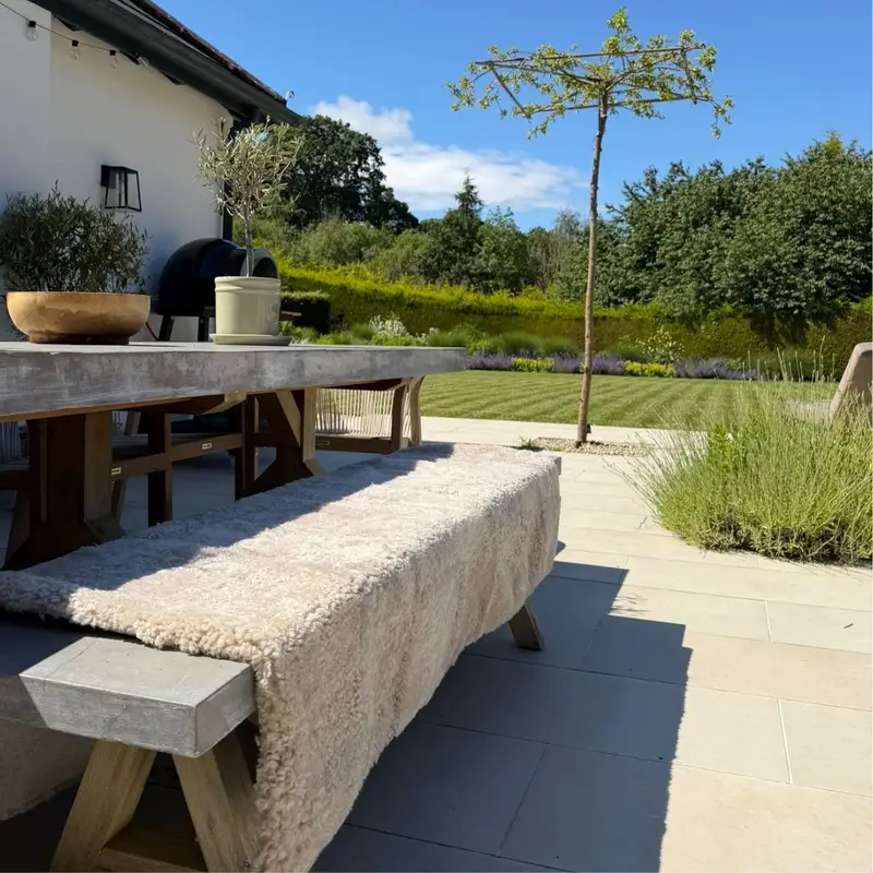 An neutral coloured shearling sheepskin throw on a concrete dining bench seat