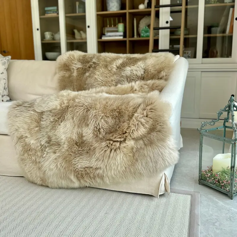 An eggshell coloured sheepskin throw strewn on a cream large sofa