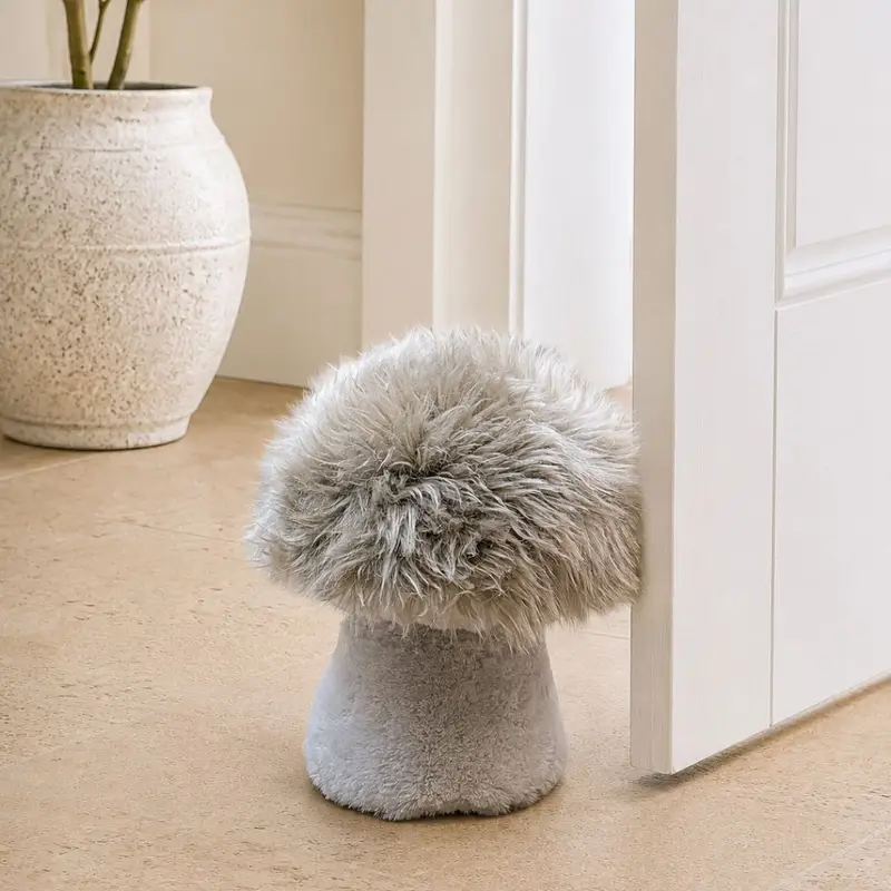 Close up of a Handmade field mushroom sheepskin doorstop with a fluffy mushroom coloured cap, velvety stalk and shorn sheepskin gills.