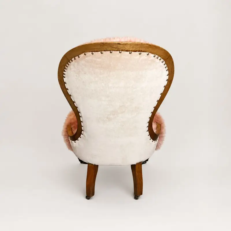Back view of an Antique Victorian walnut bedroom chair upholstered in dusky pink sheepskin with a soft pink velvet back and ceramic castors.