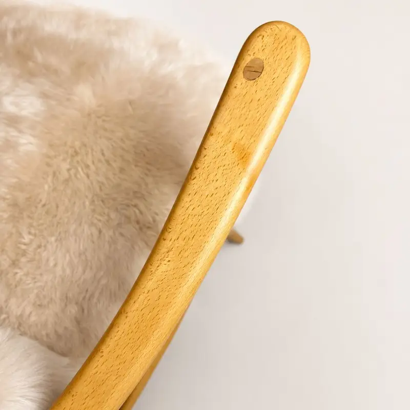 Close up 2 of arm of Ercol Model 766 lounge chair upholstered in pale Seashell sheepskin