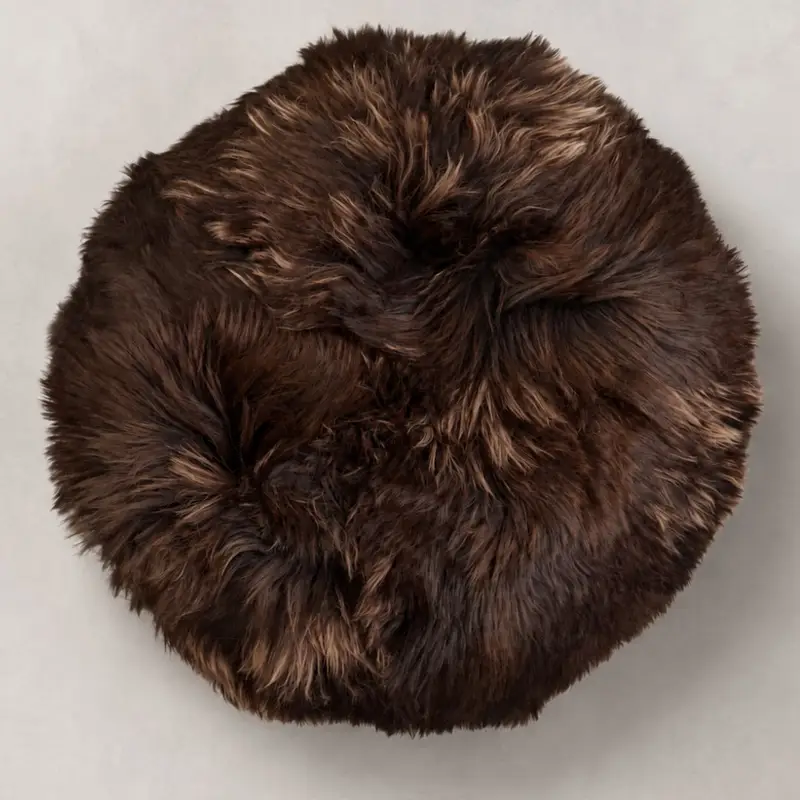 Overhead view of a chocolate sheepskin Cookie Pouffe showing natural caramel tones through the long wool.